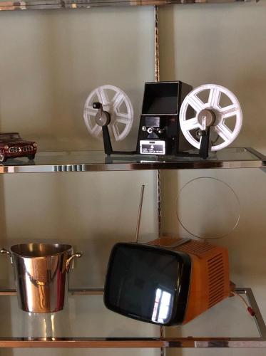 a shelf with a microwave and a tv and a fan at N°30 CHARME Apartments in Vigevano