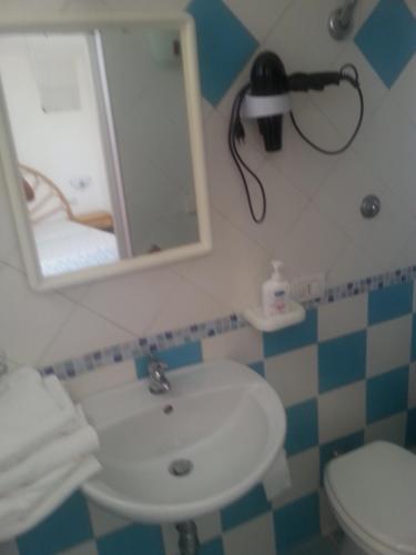 a bathroom with a sink and a mirror and a toilet at Casadelpino Residence La Piana in Ponza