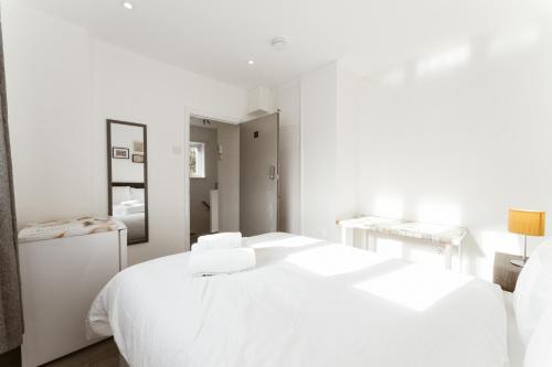 a white bedroom with a white bed and a mirror at Stepney Green beds to stay 24 in London