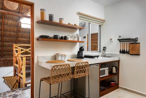 a kitchen with a counter with two chairs and a sink at Verandah Studios in Playa del Carmen