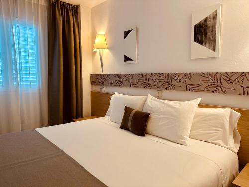 a bedroom with a bed with white sheets and pillows at LUZ Vejer Hospedería in Vejer de la Frontera