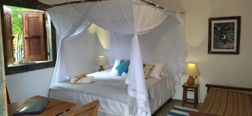 um quarto com uma cama de dossel branca em Pousada Céu de Corumbau em Corumbau