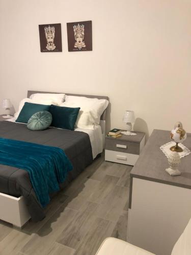 a bedroom with a bed with a blue blanket and a desk at Casa Inyco in Menfi