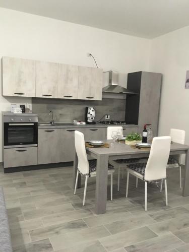 a kitchen with a table and white chairs in it at Casa Inyco in Menfi