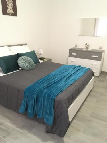 a bedroom with a bed with a blue blanket on it at Casa Inyco in Menfi