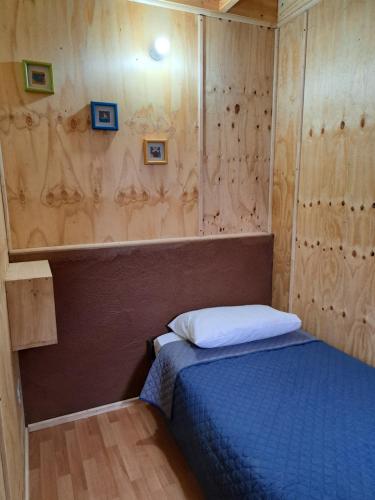 een kleine slaapkamer met een blauw bed en houten wanden bij Cabaña Don Ricardo in Coihaique