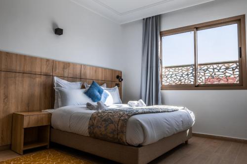 a bedroom with a bed with a wooden headboard and a window at Karam City Hotel in Dakhla