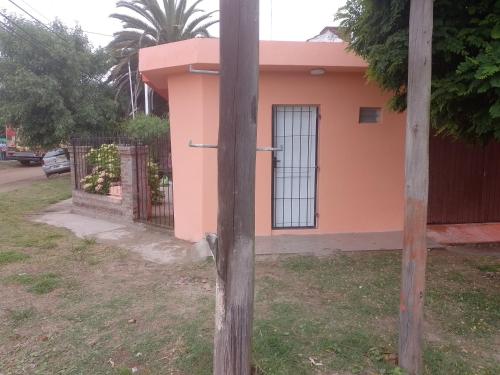 una pequeña casa rosa con una valla y un poste en La Positiva en Mar de Ajó