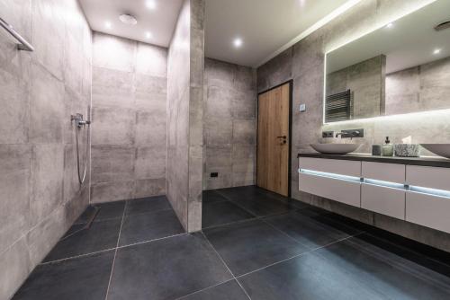 y baño con ducha, 2 lavabos y espejo. en Moderne Villa mit Whirlpool und Heimkino en Waldkirchen