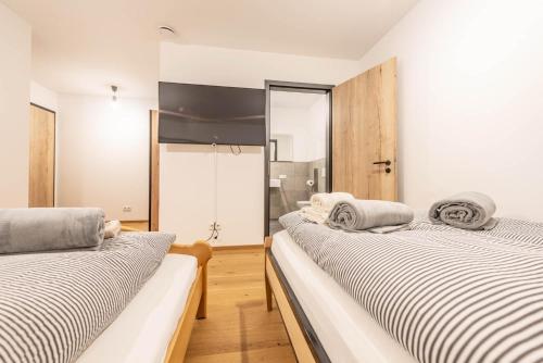 two beds in a room with white walls and wooden floors at Moderne Villa mit Whirlpool und Heimkino in Waldkirchen