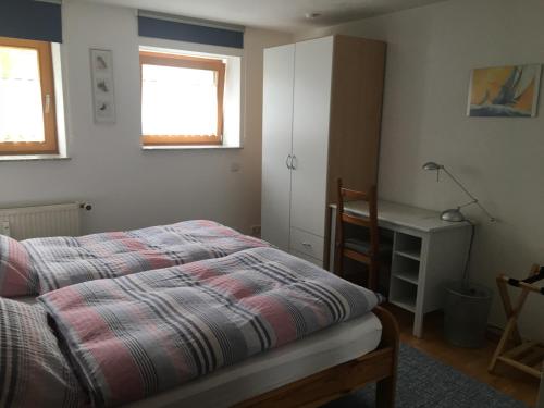 a bedroom with a bed and a desk and two windows at Ferienwohnungen Fuchssteige in Heidenheim an der Brenz