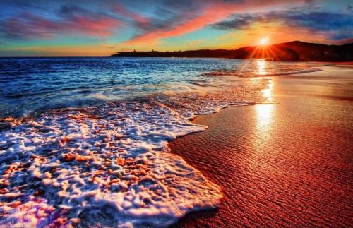 a sunset on a beach with the tide coming in at Maui Kamaole B207 in Wailea