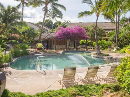 a swimming pool with chairs and palm trees at Tropical Maui Kamaole B-Bldg in Wailea