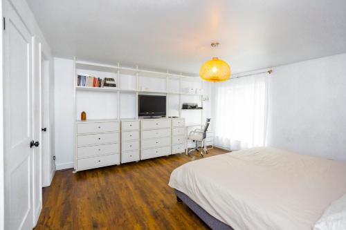 a white bedroom with a bed and a television at Cosy 3-Bedroom Home in Quiet Cul-de-Sac. in Pickering