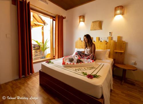 una mujer sentada en una cama en una habitación en Island Holiday Lodge, en Felidhoo 