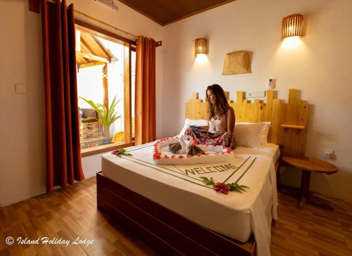 a woman sitting on a bed in a room at Island Holiday Lodge in Felidhoo 