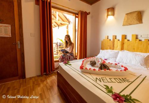 a woman sitting on a bed in a room at Island Holiday Lodge in Keyodhoo