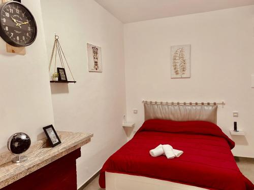 1 dormitorio con cama roja y reloj en la pared en B&B Le Sorelle, en Giffoni Valle Piana