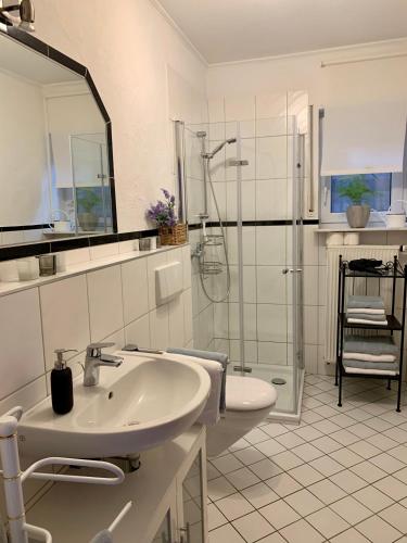a white bathroom with a sink and a shower at Ferienwohnung Kaspers in Schalkenmehren