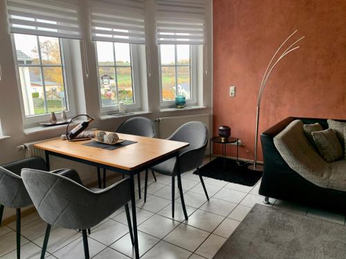a room with a table and chairs and windows at Ferienwohnung Kaspers in Schalkenmehren