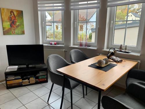 a dining room with a table and chairs and a television at Ferienwohnung Kaspers in Schalkenmehren