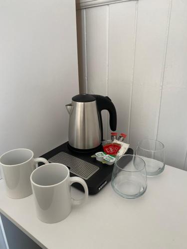 two coffee mugs and two glasses on a counter at Ship Inn Stays Ltd in Wylam