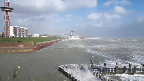 a body of water with a lighthouse and waves at De Sprink - Vakantiewoning in Zoutelande
