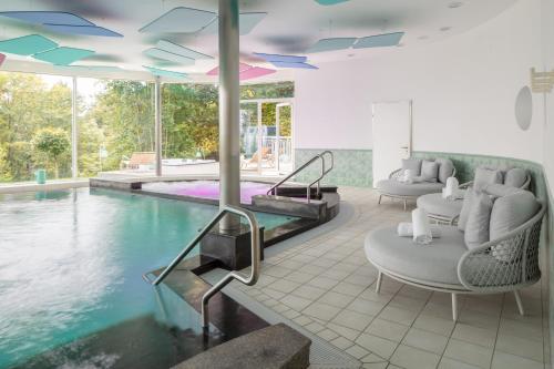 uma piscina com duas cadeiras e uma mesa e uma piscina em Hotel Waldegg - Adults only em Engelberg
