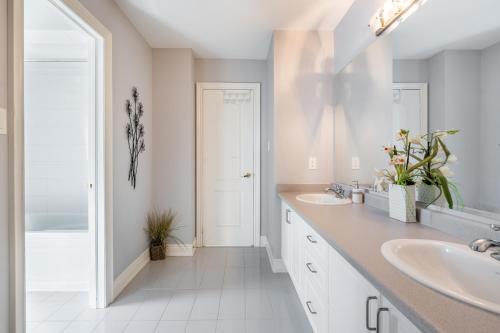 a white bathroom with two sinks and a mirror at Beautiful Family Villa, Pond Facing with Huge Backyard in Brampton