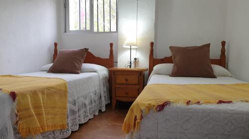 una camera con due letti e un tavolo con una lampada di Casa Rural Parajes del Chanza a Cortegana