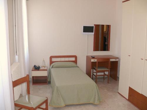 1 dormitorio con cama, escritorio y silla en Albergo Casa Del Pellegrino, en Monte SantʼAngelo