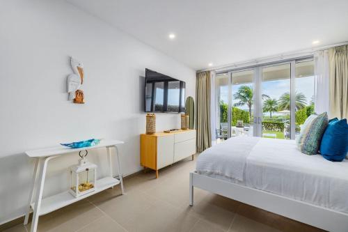a white bedroom with a bed and a window at Azure Beach Residences in Palm-Eagle Beach