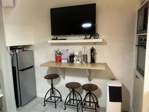 - une cuisine avec deux tabourets de bar et une télévision murale dans l'établissement Maison confortable à Arques-la-Bataille avec parking, à Arques-la-Bataille