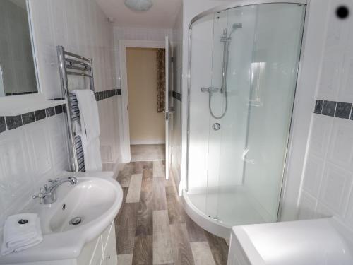 a white bathroom with a sink and a shower at Meadowfields in Kidderminster