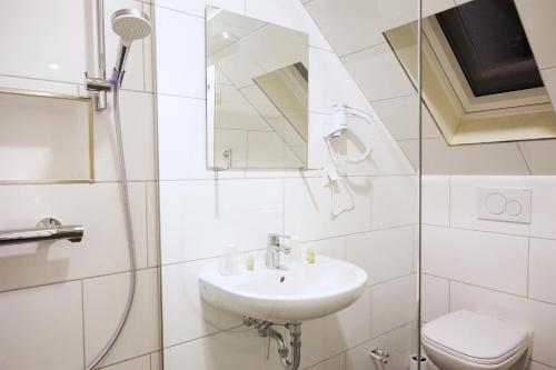 a white bathroom with a sink and a toilet at JJ Hotel Hannover-City-Pension in Hannover