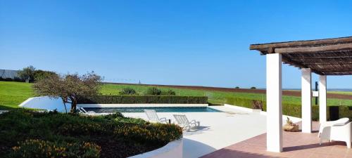 a swimming pool with chairs and a pavilion at Monte Da Morena Agro-Turismo in Serpa