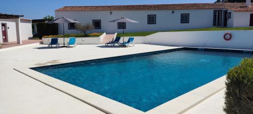 a swimming pool with chairs and a house at Monte Da Morena Agro-Turismo in Serpa