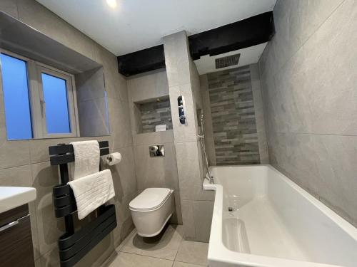 a bathroom with a tub and a toilet and a sink at Cragside Cottage in Troutbeck