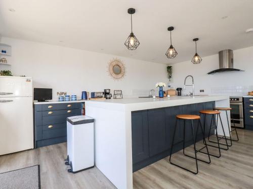 a kitchen with blue cabinets and a white refrigerator at Camelot in Tintagel