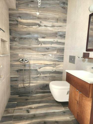 a bathroom with a toilet and a wooden wall at Anna Studios in Myrties