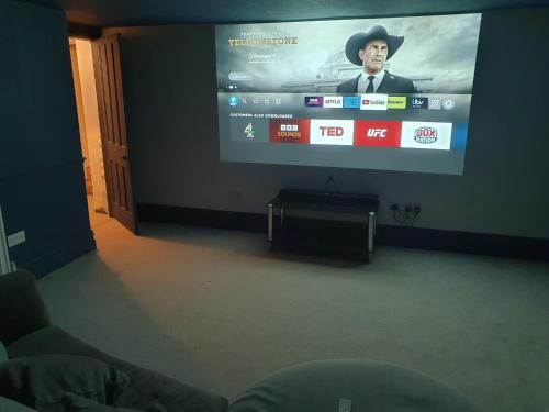a flat screen tv with a man in a hat on it at Brylie House, Large Central family home in Skipton