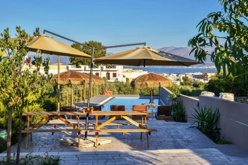 a patio with a table and umbrellas and a pool at VillaBayViewCrete in Hersonissos