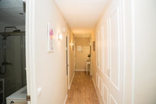 un corridoio con pareti bianche e pavimenti in legno di Gallimó Apartaments a L'Ampolla