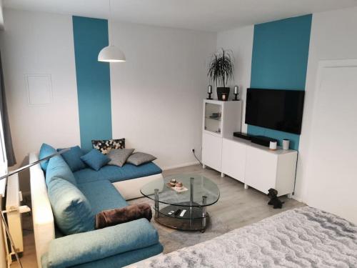uma sala de estar com um sofá azul e uma mesa de vidro em Altes Gut Berka em Sondershausen