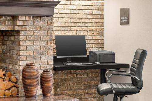a desk with a computer on a brick wall at AmericInn by Wyndham Sauk Centre in Sauk Centre