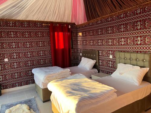 two beds in a room with red walls at Wadi Rum Desert Adventures in Wadi Rum