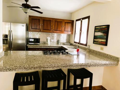 a kitchen with a granite counter top with two bar stools at Sueños de Amor! Hermoso y Acogedor lugar in Quepos