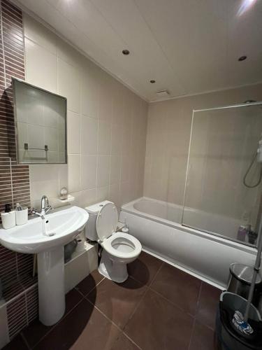 a bathroom with a toilet and a sink and a tub at Amicable Double Bedroom in Manchester in shared house in Ashton under Lyne