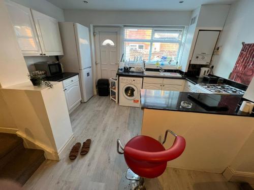 uma cozinha com uma cadeira vermelha em frente a um balcão em Amicable Double Bedroom in Manchester in shared house em Ashton-under-Lyne