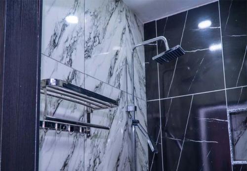 ein Bad mit einer Dusche und einer Marmorwand in der Unterkunft Westpark Luxury Apartments in Ikeja